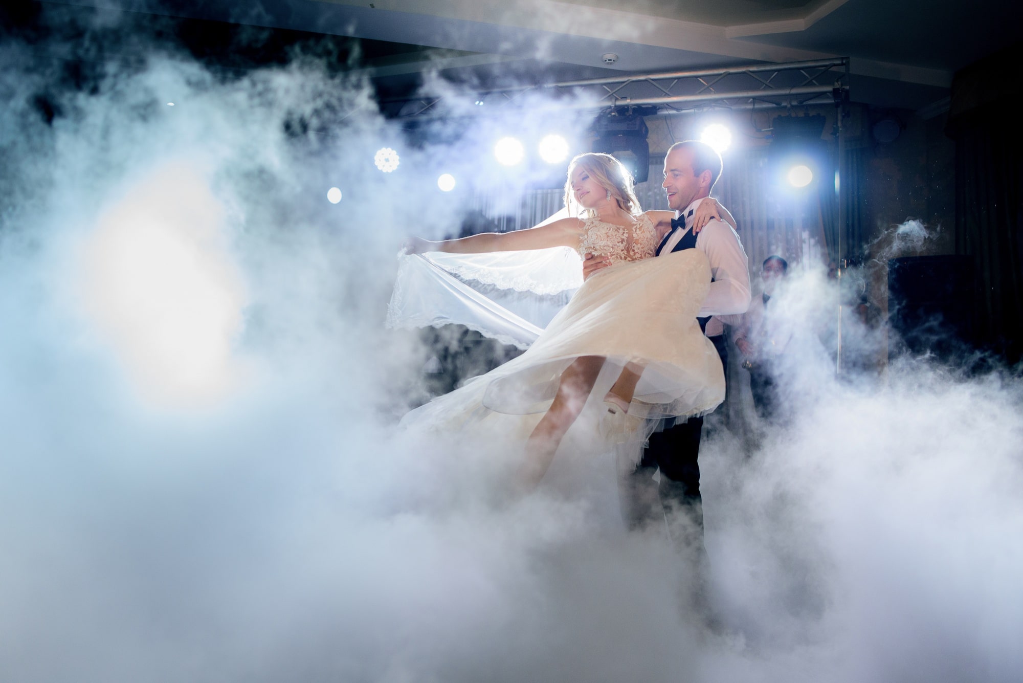 El novio hace girar a la novia en el baile del humo durante la boda